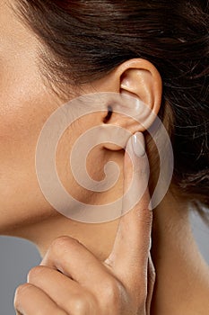Close up of young woman pointing finger to her ear