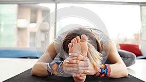 Close up of young woman practicing yoga, sitting in Head to Knee Forward Bend exercise, Janu Sirsasana pose, working out