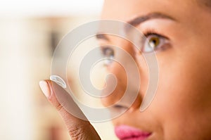 Close up of a young woman putting contact lens in her eye close up