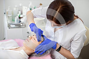 Close up of young woman receiving serum oil treatment in beauty salon. Female doctor cosmetologist applying lotion serum