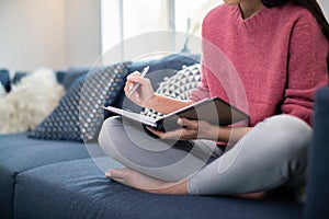 Close Up Of Young Woman Relaxing On Sofa At Home Writing In Journal