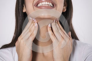 Close up of young woman rubbing her inflamed tonsils, tonsilitis problem, cropped. Woman with thyroid gland problem, touching her