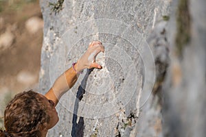 Close-up of a young woman`s hand holding onto the stone while climbing