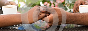 Close-up of young woman`s hands holding her boyfriend`s hands while having coffee at a cafe