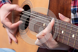 Close-up of a young woman`s hands playing guitar