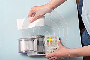 Close-up of a young woman`s hands tearing a check from a cash register after purchasing a product on a market or store