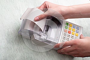 A young woman`s hands tearing a check from a cash register after purchasing a product, entering a discount on a market