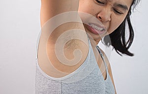 Close up of young woman showing her unshaved armpit and offensive face  on grey background. Concept of Health care for