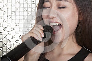 Close-up of young woman singing into a microphone at karaoke