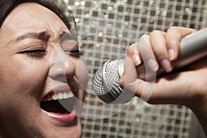 Close-up of young woman singing into a microphone at karaoke