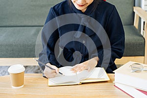 Close up young woman sit at table hold pencil take notes to paper notebook working studying. Female student