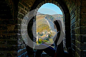 CLOSE UP: Young woman sits by a window and observes the Great Wall of China.