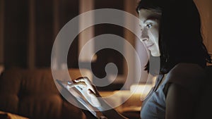 Close-up of young woman surfing tablet computer at night at home