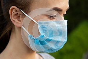 Close-up of a young woman with a surgical mask on her face