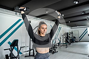 close-up young woman trains muscles on exercise machine in the gym.