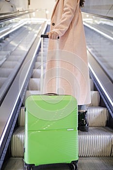 Close up for young woman traveler tourist with luggage standing on escalators in train station.