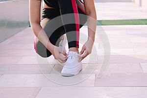 Close up of young woman tying her laces before a run