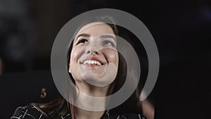 Close up of Young woman is watching movie and talking with somebody at cinema