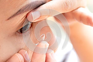 Close up young woman wearing contact lens. asian woman putting eye lenses with hands