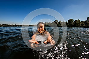 Close-up of young woman who floats on the river on wakesurf board photo