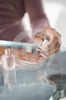 Close up of a young woman who paints her own nails with pearl la