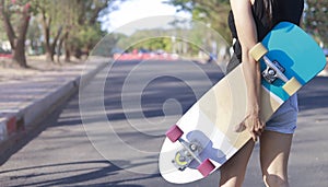 Close up on young women hand hold skateboard, surf skate on public park background. Free relax skateboard trendy concept. Fashion