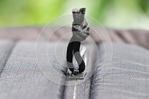 Close up of a zipper from bag with thread piece to open and close the zips