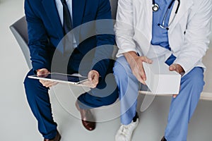 Close upf on legs of pharmaceutical sales representative talking with doctor in medical building, presenting new