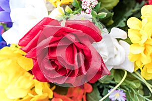 Close view of an assortment of artificial flowers with a red rose in the center