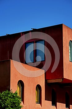 Close view of block style construction or architecture with red brown stucco exterior or facade with windows and front