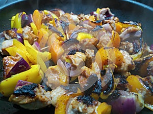 Close view of chicken skewers scorching in a pan