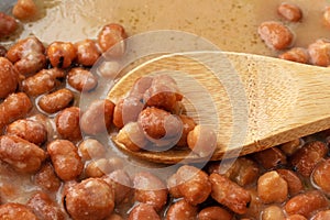 Close view of fava beans in a broth with a wood spoon in the food