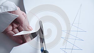 Close view of female hands cutting a pattern of dress in atelier