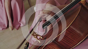 Close view of female violoncellist playing on the strings with fiddlestick