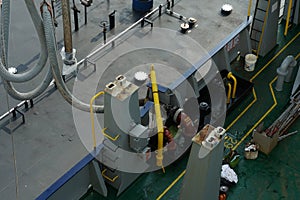 Close view on fuel hose of bunker barge on crane connected to container vessel in bunker station.