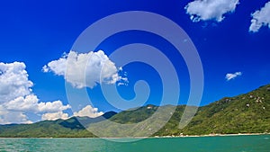 close view of green hilly island cloud shadows against blue sky