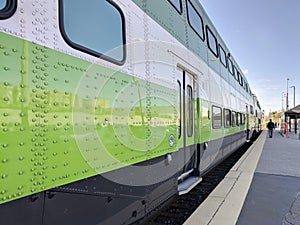 Close view of green train arriving leaving train station platform. Man walking way from the station.