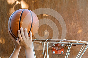 Close view of hands throwing a ball into a basketball basket, teenage boy playing at home in the backyard, outdoor activities on