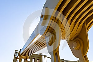 Close view of a joint in a self anchored suspension bridge, heavy metal supports painted yellow, blue sky copy space photo