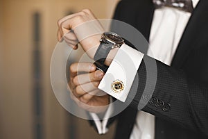 Close view of the luxury watches on the hand of a handsome businessman in a tuxedo and in a shirt with cufflinks photo