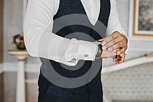 Close view of the luxury watches on the hand of a handsome businessman in a tuxedo and in a shirt with cufflinks