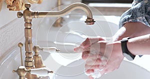 Close view of male hands washing with soap under flowing faucet of washstand