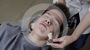 Close view of man receiving skin rejuvenation with facial massage with snails