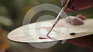 Close view of mixing a watercolors on wooden palette on nature