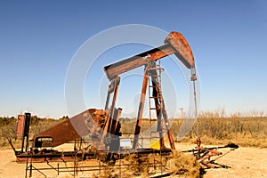 Old rusty oil derrick in sunlight with blue sky