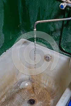 Close view of old stained water tap and rusted bathtub with selective focus and blur