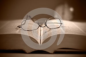 Close View of Reading Eyeglasses on Large Book Sepia Toned