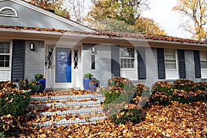 Close view of residential home inundated with fall leaves in need of leaf removal and lawn cleanup