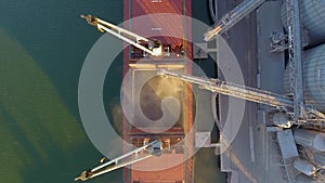 Close view of ship loading grain crops on bulk freighter via trunk to open cargo holds at silo terminal in seaport