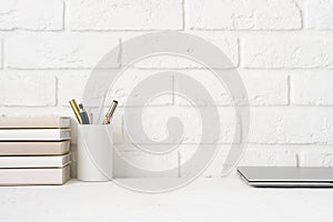 Close view of simple workspace with laptop, notebooks and stationery